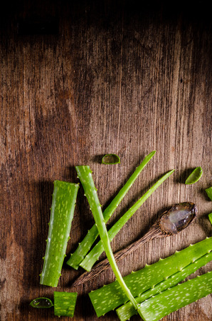 aloe vera gel on wooden spoon with aloe vera on wooden table.の写真素材