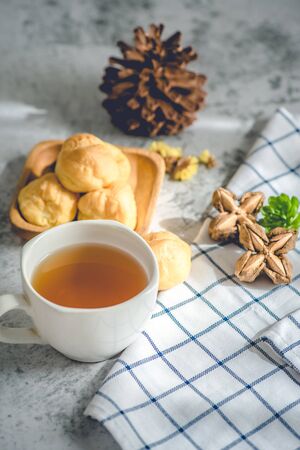 A Cup of freshly brewed tea,escaping steam,warm soft light, with Eclair sweet on the table.の写真素材