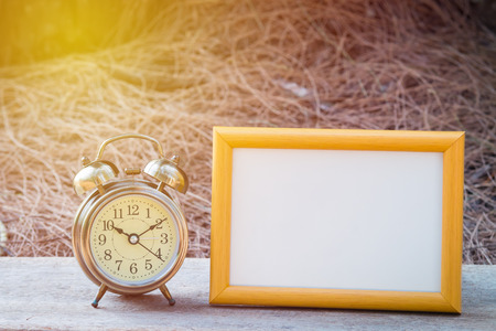 Retro clock and gold frame on wood tableの写真素材