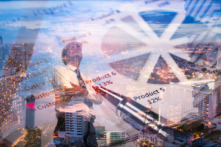 Businessman standing and looking at night City. Graphs are seen in the foreground. Concept of successful business.の写真素材