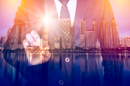 businessman pointing index finger, action of touch screen with rays. Double exposure with big city building in business center of capital.の写真素材