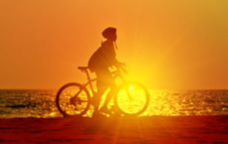 Blurred silhouette people with bicycle on sunset beach