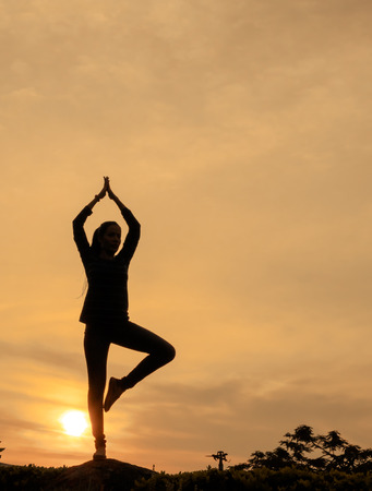 Silhouette women show hands sunset background.の写真素材