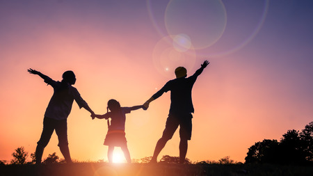 Silhouette happy family father,mother and daughterin the park at sunset with sun flareの写真素材