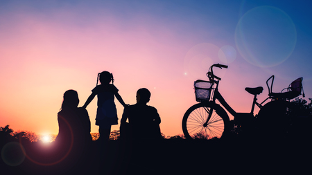 Happy Family,father,mother and daughter with bicycle at sunsetの写真素材