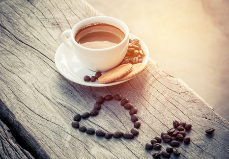 Cup of espresso with cracker and coffee bean on old wood in morningの写真素材