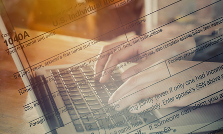 Double Exposure hand typing laptop with US tax form / taxation conceptの写真素材