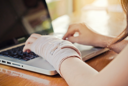 Woman arm splint mild injuries from accidents using laptopの写真素材