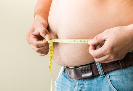 The fat man took off his shirt and measured the big belly tape.の写真素材