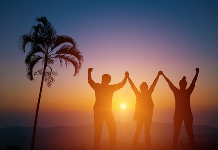 Silhouette of happy business team making high hands at sunsetの写真素材