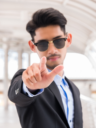 Businessman wearing sunglass and point finger (selective focus)の写真素材