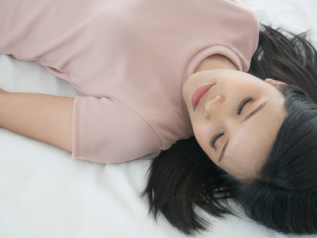 Beautiful girl sleeping on the bed. She makeup and wearing the false eyelashes.の写真素材