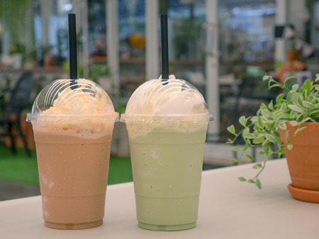 Green tea frappe and ice blended coffee on white tableの写真素材