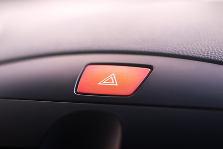 Car emergency warning light button in front car console.Visible red triangle emergency symbol.