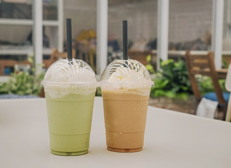 Green tea frappe and coffee frappuccino on white tableの写真素材