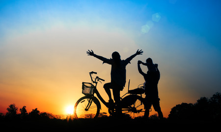 Silhouettes of happy sitting at the park in the evening. with sun flare. Concept of friendly family.の写真素材