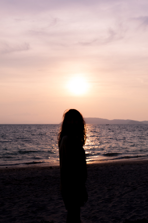 Silhouette woman side stand on a beach with sunsetの写真素材