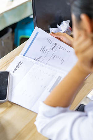A woman looking at the invoice with concernの写真素材