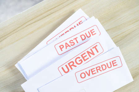 Debt letters that are collected on past overdue bills and final announcements on the table. Red writing to represent the struggle against economic unemployment.の写真素材