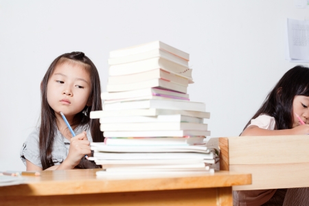 Little Asian girl thinking while studyingの写真素材