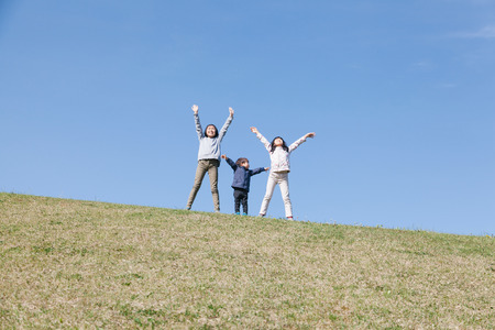 three kids playing on green hillの写真素材