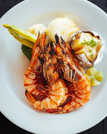 Fresh grilled shrimps with vegetable on white plateの写真素材