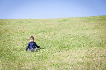 a boy sitting on green hillの写真素材