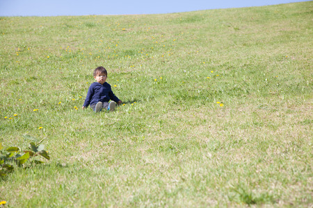 a boy sitting on green hillの写真素材