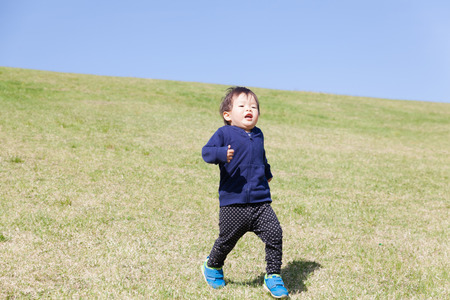 a boy playing on green hillの写真素材