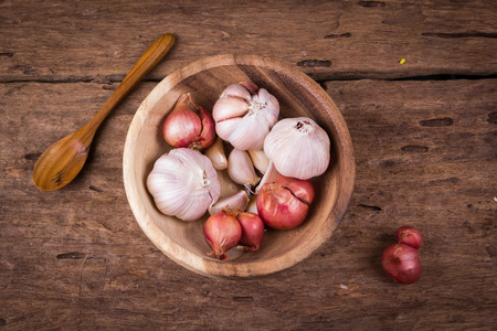 Garlic and red onions in a wooden bowl.の写真素材