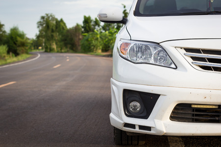 front of dirty white car parking on the asphalt roadの写真素材