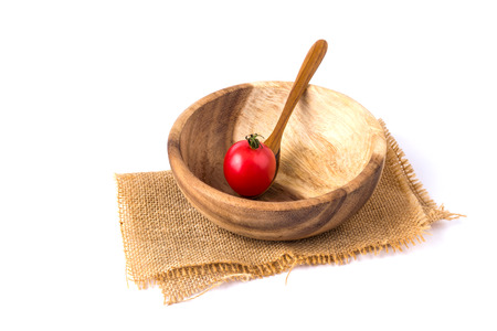 cherry tomatoes in the wooden spoon in a wooden bowl on a white background.の写真素材