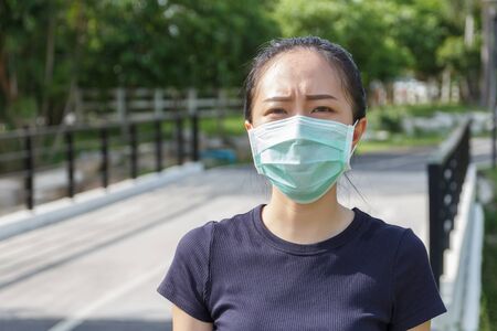 The ypung woman in medical protective mask relaxing in the park.  campaign to use protective mask from COVID19の写真素材
