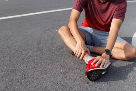 Sport man holding ankle in pain due to sprained ankle. Injury from workout concept