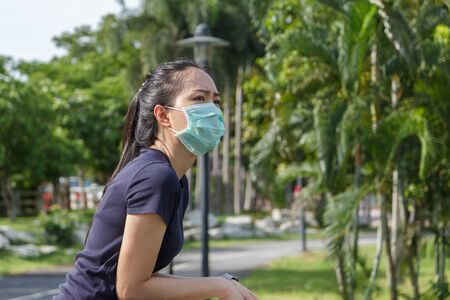 The ypung woman in medical protective mask relaxing in the park.  campaign to use protective mask from COVID19の写真素材