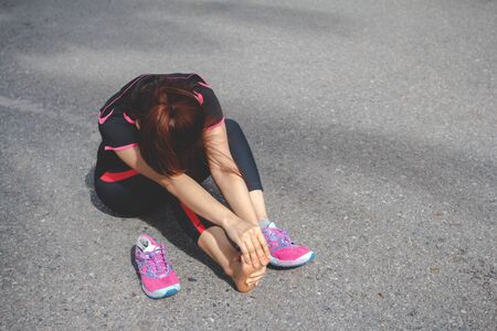Sport woman feeling pain in her foot after running. Injury from workout conceptの写真素材