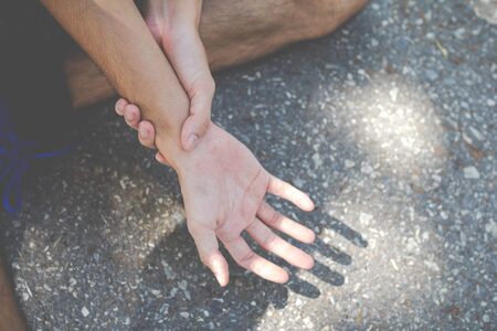 Closeup of male arms holding her painful wrist because exercise - workout concept , .Injury from...