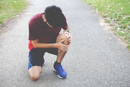 Close up of Sport man suffering with pain on sports running knee injury after running.Injury from workout concept.の写真素材