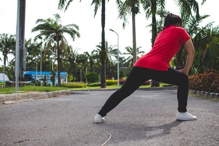 Young woman runner stretching legs before run - workout concept