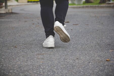 The woman jeans and sneaker shoes walking on the road.