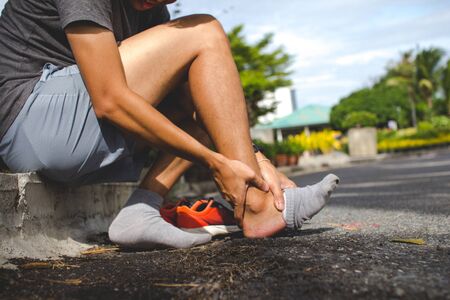 Sport man holding ankle in pain due to sprained ankle.Injury from workout concept.の写真素材