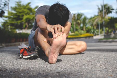 Sport man feeling pain in his foot after running.Injury from workout concept.の写真素材