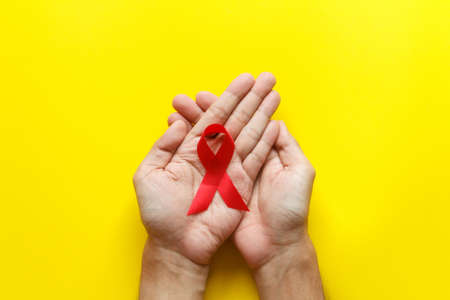 red AIDS awareness ribbon on yellow paper background. World aids day and healthcare and medicine conceptの写真素材