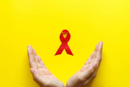 red AIDS awareness ribbon on yellow paper background. World aids day and healthcare and medicine conceptの写真素材