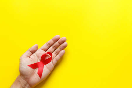 red AIDS awareness ribbon on yellow paper background. World aids day and healthcare and medicine conceptの写真素材