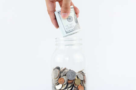 Hand put mock up cash in to glass bottle.finance, economy concept. saving money concept.の写真素材