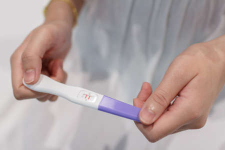 Hand holding the pregnancy test is showing a positive result.の写真素材