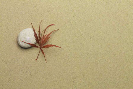 maple leaf and zen stone on sandの写真素材