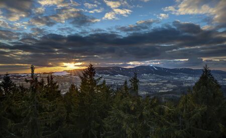 Dramatic Libeerc sunset sky with illuminated clouds in the mountains. Dark black silhouette of...