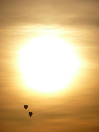 Photo of two hot air balloons floating next to a setting sunの写真素材